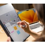 High-tech digital tablet with stylus showing planning app, in front of laptop on a workspace.