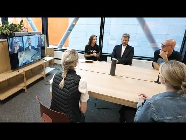 Video conference meeting with multiple participants in a modern office setting.