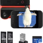 Penguin caught on smartphone screen with bird behind, digital camera, batteries, SD card, and portable charger displayed.