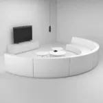 Webinar room with curved white sofa, wall-mounted TV, and small tables, ideal for virtual meetings and live streaming setups.